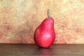 Still life of a rustic red pear against an orange background Royalty Free Stock Photo