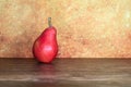 Still life of a rustic red pear against an orange background Royalty Free Stock Photo