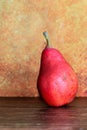 Still life of a rustic red pear against an orange background Royalty Free Stock Photo