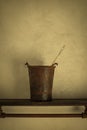 Still life of rusty bucket with brush on shelf in soft warm light