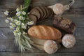 Still life of rye bread with sesame and buns and a loaf of white bread with ears and flowers on a rustic wooden background, top vi