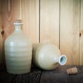 Still life of sake bottles with light on wood background. Royalty Free Stock Photo