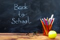 Still life with school books, pencils and apple against blackboard with 