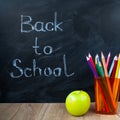 Still life with school books, pencils and apple against blackboard with 