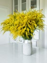 Still life of solidago goldenrod wildflowers in a vase on a white kitchen table.