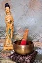 Sound bowl and old sculpture of asian woman on flowery background