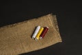 Still life with spools of thread of three colors on a folded burlap cloth on a black surface Royalty Free Stock Photo