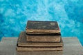 Stack of old books on a wooden table with blue wall background. Royalty Free Stock Photo