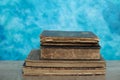 Stack of old books on a wooden table with blue wall background. Royalty Free Stock Photo