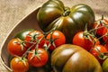 Still life of stupendous ripe sweet marmalade tomatoes along with bunches of cherry tomatoes in a wooden basket on brown burlap Royalty Free Stock Photo