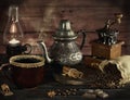 Still life in the style of an old photograph with a coffee grinder, coffee beans with an old lamp and a kettle with a cup with