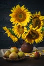 Still life with sunflowers in a clay pot and pears on the background of a wooden wall