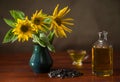 Still life with sunflowers in a vase, sunflower oil in a glass decanter and gravy boat, and a bunch of sunflower seeds Royalty Free Stock Photo