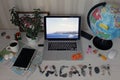 Still life on the table with a laptop and a stone inscription vacation