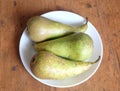 Three long ripe green pears on white pale top view closeup