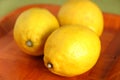 Still life with three ripe yellow lemons on brown tray Royalty Free Stock Photo