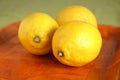 Still life with three ripe yellow lemons on brown tray Royalty Free Stock Photo