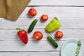 Tomatoes, cucumbers, peppers and white plate  on an old wooden light rustic table with an old bag Royalty Free Stock Photo