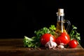 Still life of tomatoes, garlic and olive oil on wooden boards. On a black background. Royalty Free Stock Photo