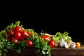 Still life of tomatoes, garlic and parsley on wooden boards. On a black background. Royalty Free Stock Photo