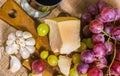 Still life - top view of yellow and red muscat grape, cheese, garlic and a glass of wine on a wooden board and canvas Royalty Free Stock Photo