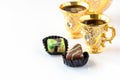 Still life with traditional golden arabic coffee set with dallah, cup and chocolate candy. White background Royalty Free Stock Photo