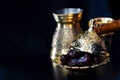 Still life with traditional luxury golden arabic coffee set with jezva, cup and dates. Dark background. Ramadan concept