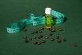 Still life transparent bottle of massage anti-cellulite oil, measure tape and coffee beans scattered on green background Royalty Free Stock Photo