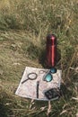 Still life of a traveler. Map, magnifier, binoculars, pen, glasses and a thermos in the grass. Royalty Free Stock Photo