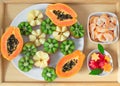 Still life. A tray with papaya, kiwi, apples. Pieces of tangerines and watermelon in plates. Royalty Free Stock Photo