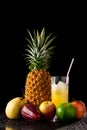 Still life with tropical fruits and glass of juice on a black r Royalty Free Stock Photo