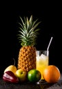 Still life with tropical fruits and glass of juice on a black r Royalty Free Stock Photo