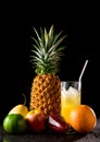 Still life with tropical fruits and glass of juice on a black r Royalty Free Stock Photo