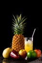 Still life with tropical fruits and glass of juice on a black r Royalty Free Stock Photo
