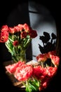 Still life of tulips in a vase with shadow in front of a mirror.