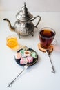 Turkish delight on a black antique plate, Moroccan teapot, honey and tea on a white table