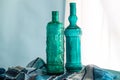 Still life with two hand crafted blue glass wine bottles made of recycled Spanish glass in front of window - horizontal image with Royalty Free Stock Photo