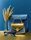 Two handbags, sunglasses and dried flowers in blue and gold.