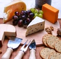 Still life 3 types of cheese roquefort cheese, red and green grapes, crackers, walnuts, cheese utensils on wooden plate Royalty Free Stock Photo