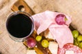 Still life - upper shot of yellow and red muscat grape, cheese, salami and a glass of red wine on a wooden board and canvas Royalty Free Stock Photo