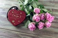 Pink roses and box with sweets on a wooden table Royalty Free Stock Photo