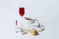 A still life with a white ceramic cup of coffee, a faded rose, a coral necklace, a lipstick, a box with the silver