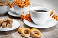Still life white Cup with coffee and pieces of cane sugar with bagels on a vintage wooden table with bunches of Rowan