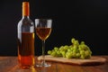 Still life with white juicy grapes, bottle of white wine without any label, and one wine glass. Royalty Free Stock Photo