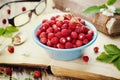 Still life with wild strawberry in blue bowl and old books on rustic table, sweet berry for summer dessert, Fragaria