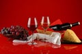 Still life with wine, cheese and grapes on a red background