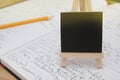Still life, wooden chalkboard label over opened notebook. Wooden table background. Copy space. Royalty Free Stock Photo