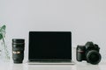 Still life working from home desk with professional photographic equipment, camera, lens, computer monitor, electronics indoors