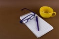 yellow cup, glasses,pen and opened notebook with empty sheet Royalty Free Stock Photo