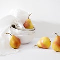 Still life with yellow-red pear Duchess in pile of bowls and a white embroidered napkin Royalty Free Stock Photo